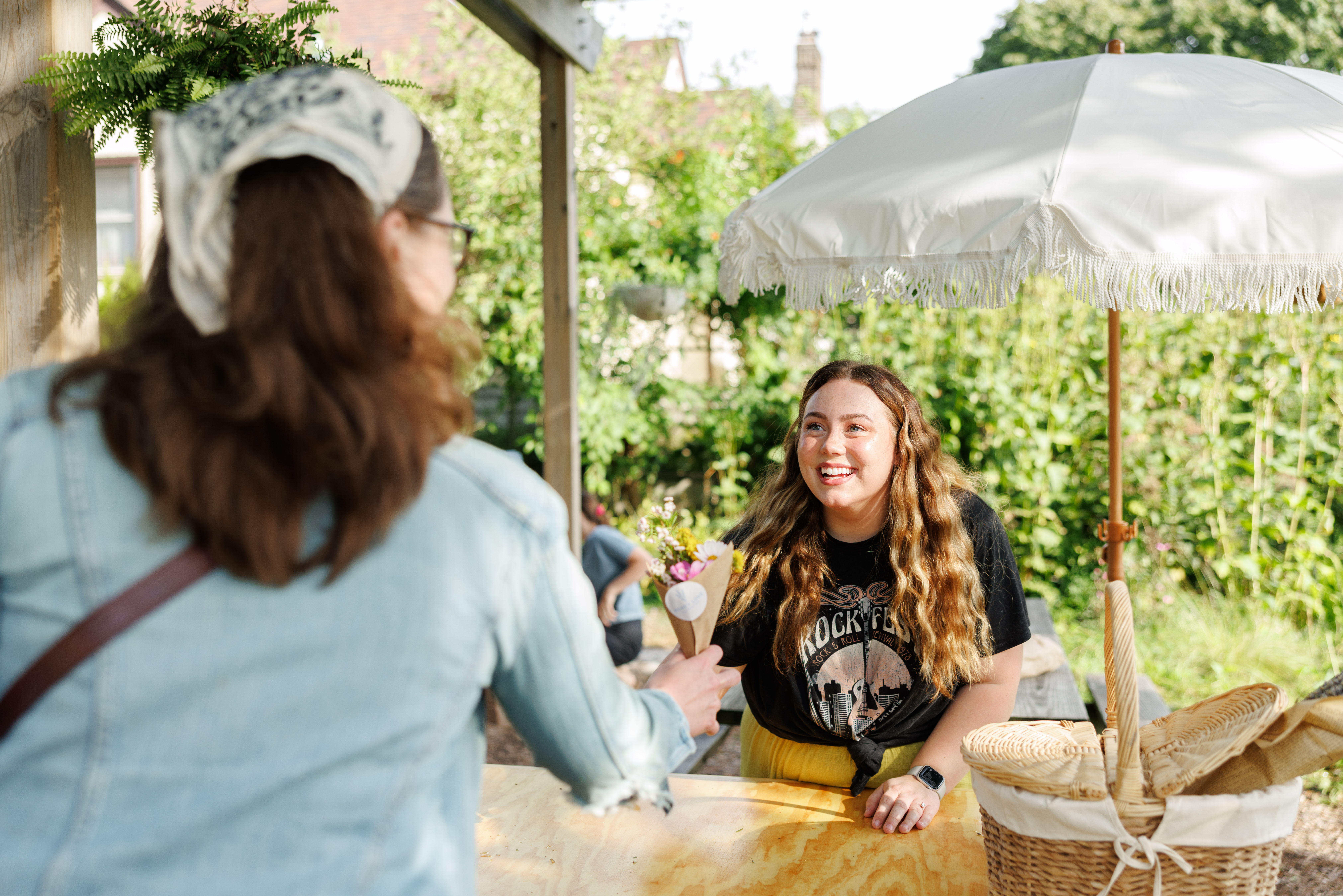 Owner of a traveling flower cart hands a bouquet of wildflowers to a client at a local pop-up event outside of Karol Coffee in Saint Paul, Minnesota.